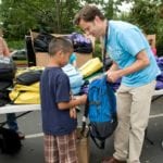 adult giving child a backpack