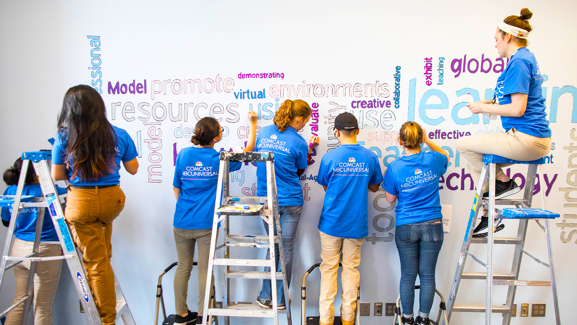 Comcast Cares Day volunteers paint a mural.