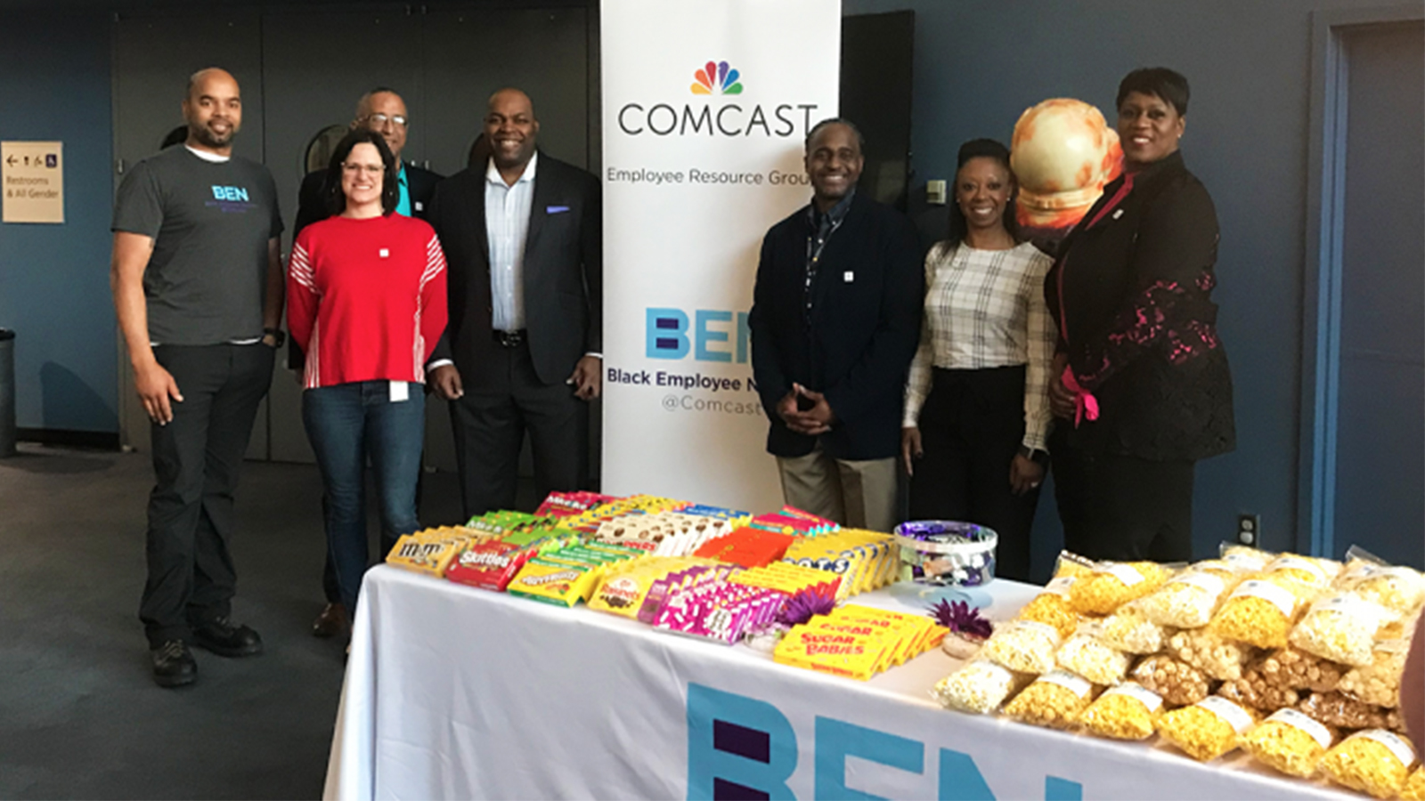 The Comcast Employee Resource Group and the Comcast Black Employee Network standing in-front of a Comcast branded banner.