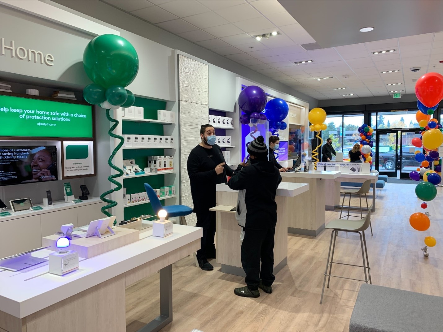 An Xfinity store employee wearing a mask helps a customer in an Xfinity store.