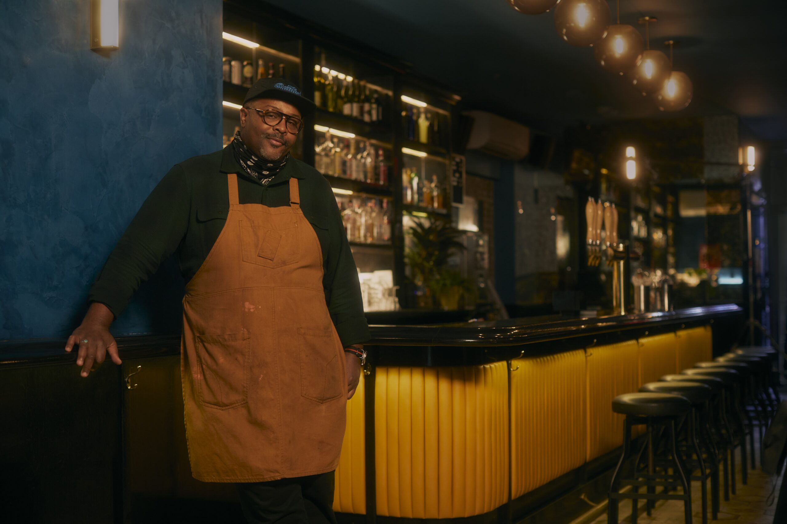 An African-American man stands at the front of a bar.