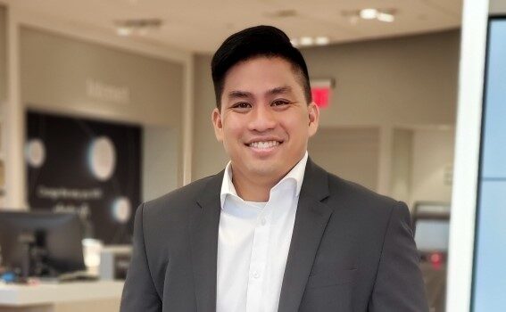 Oliver Hoang wears a suit and smiles in an Xfinity store.