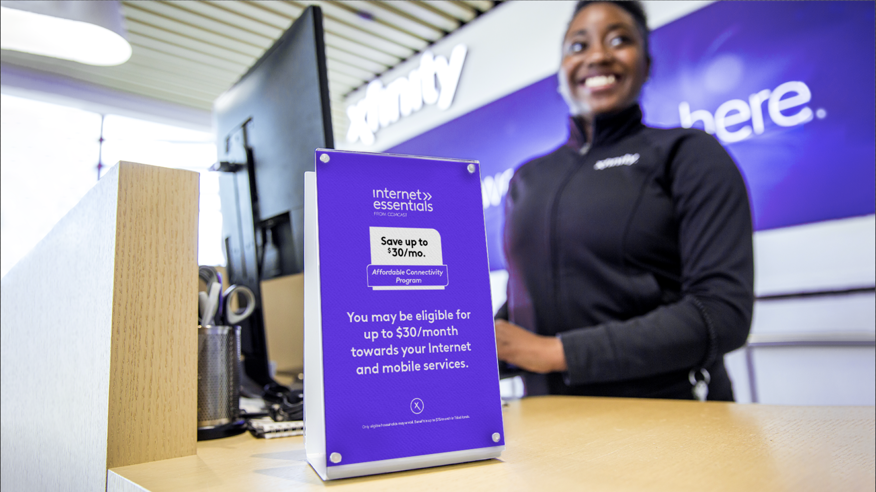 A woman stands in an Xfinity store at a computer.