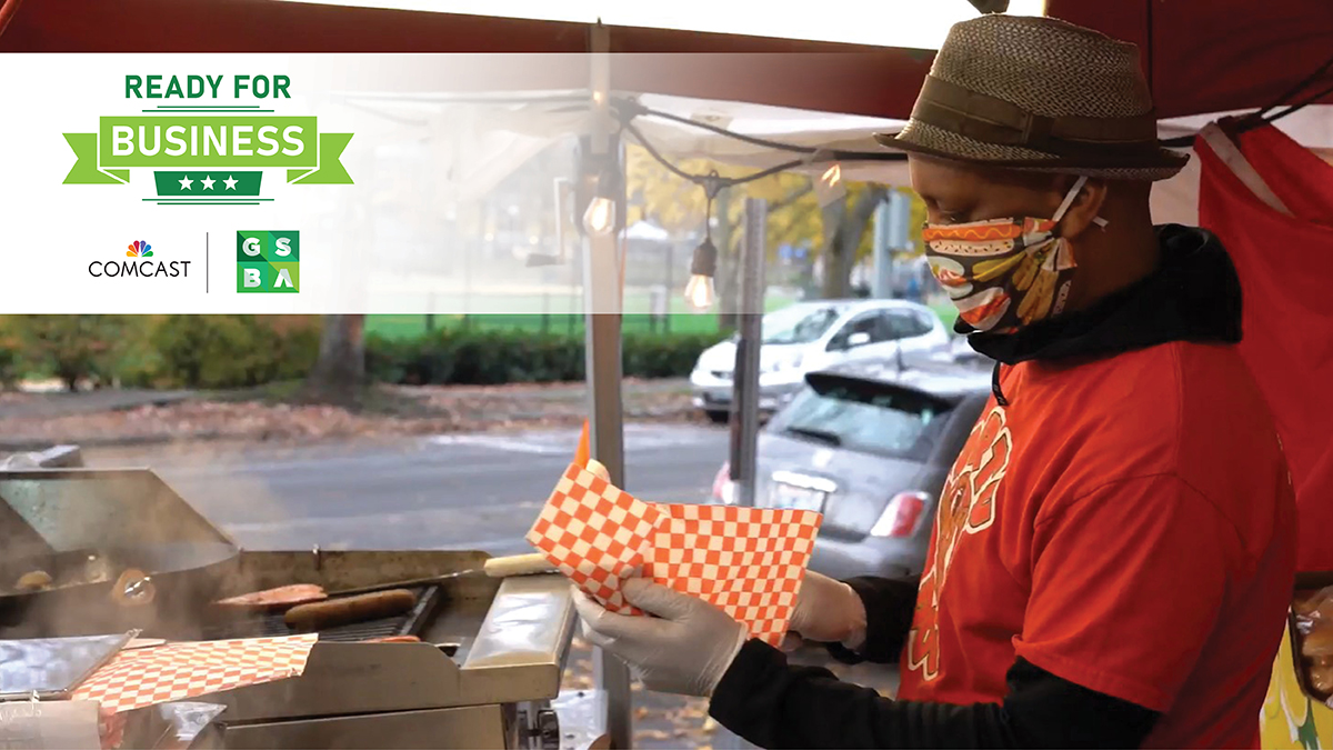 A man wearing a mask fills a food wrapper with food in a parking lot