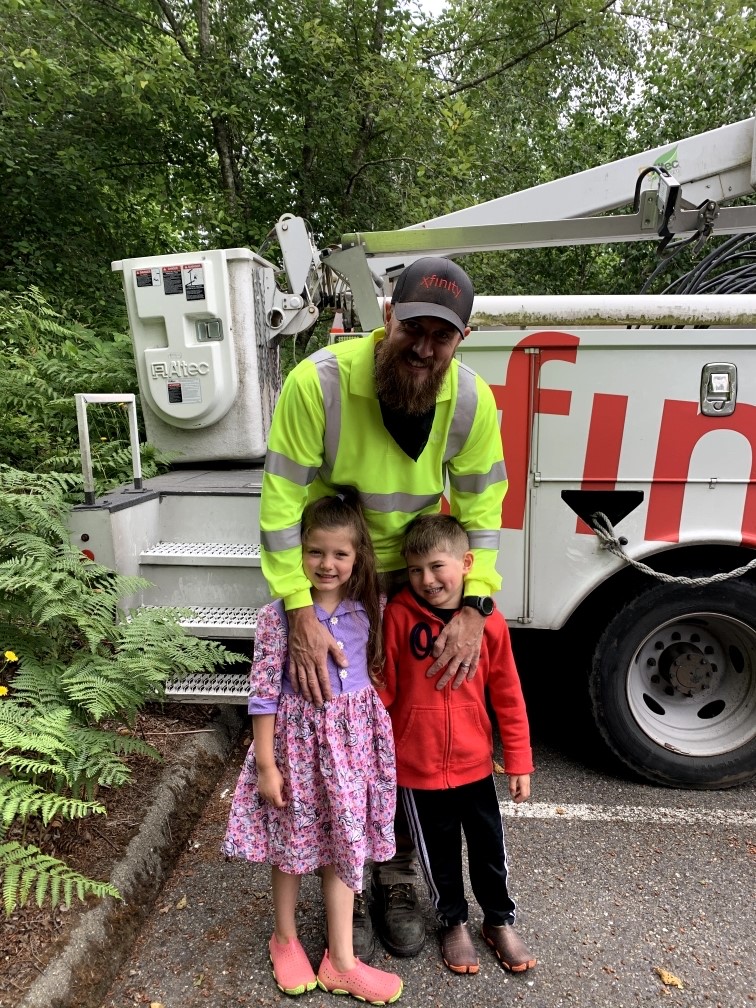 Comcast technician, Devin Fernandez smiles with his son and daughter in front of Comcast truck.