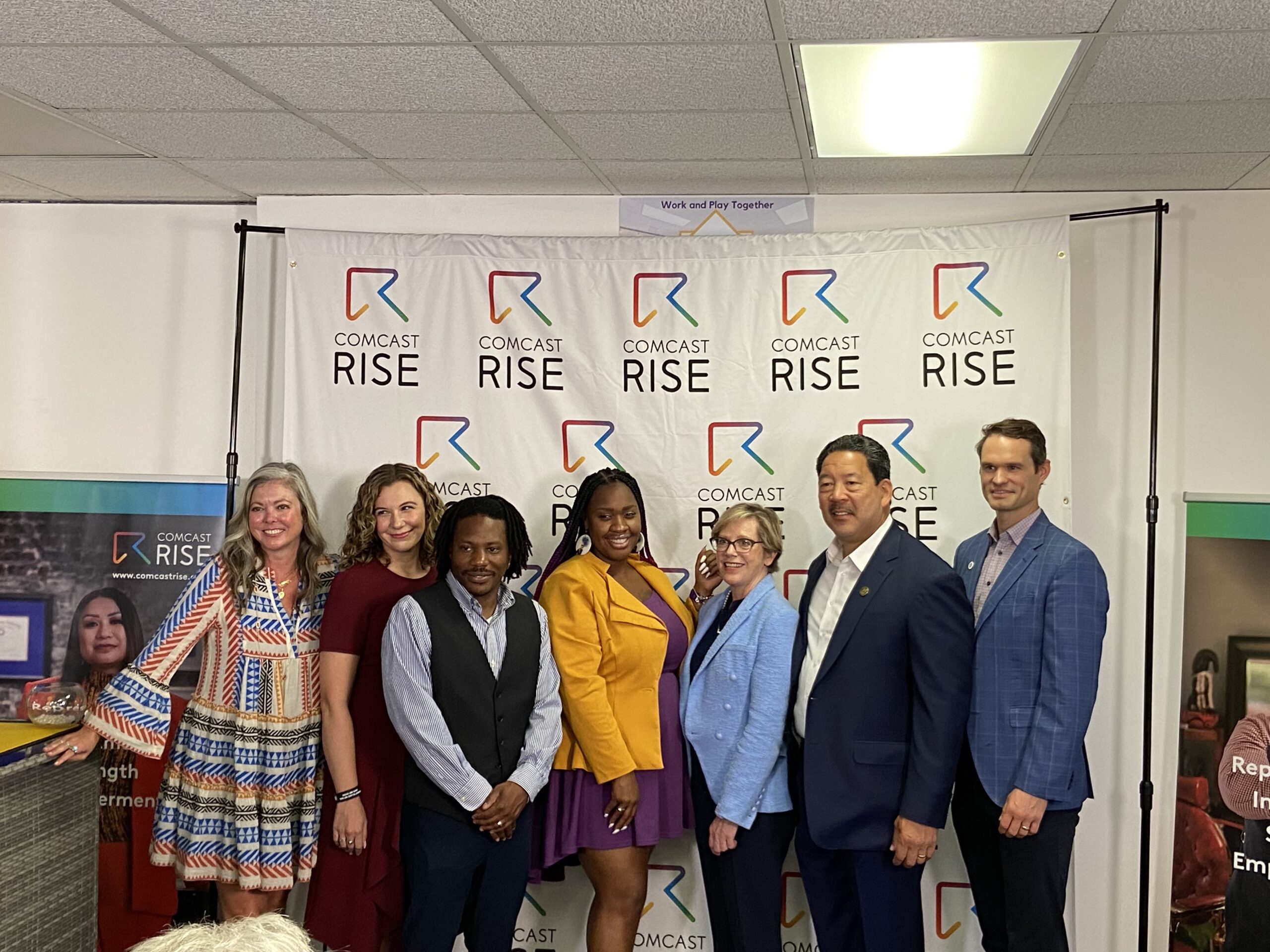 Seattle and Tacoma leaders pose in front of a Comcast RISE banner.