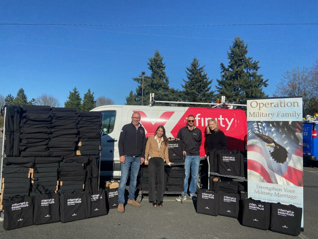 Mike Schindler of Operation Military Family stands with an Xfinity van, laptops, and Comcast staff members.