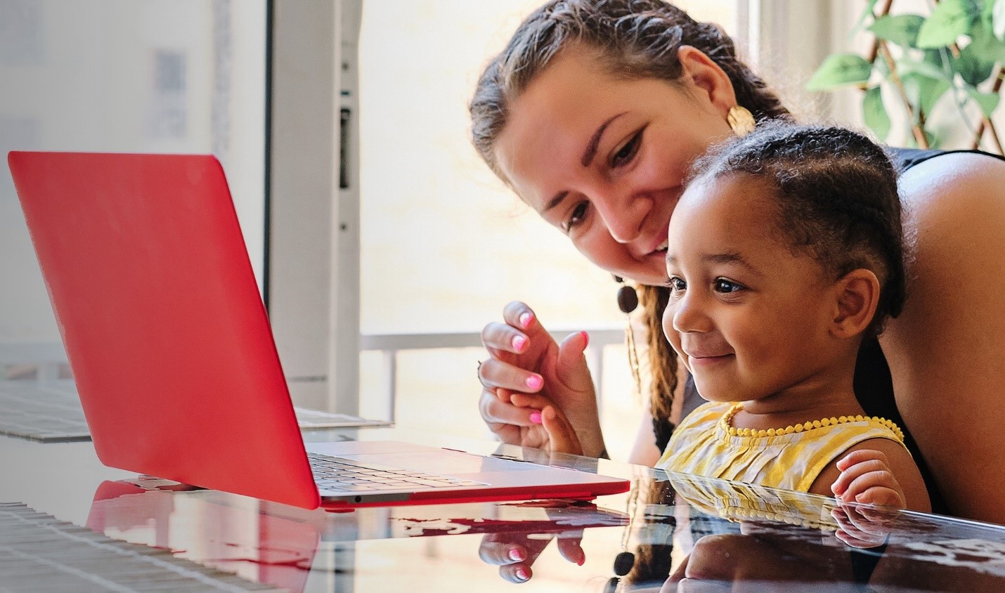 A woman and child look at a computer.