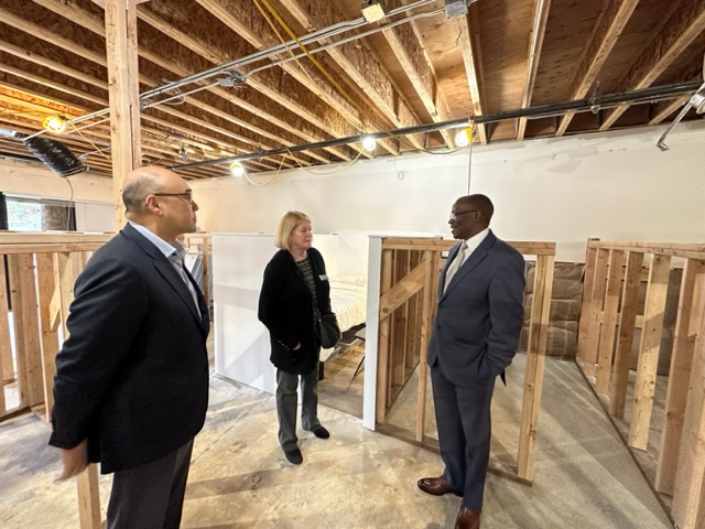 Three Friends of Youth reps stand in a building being built.