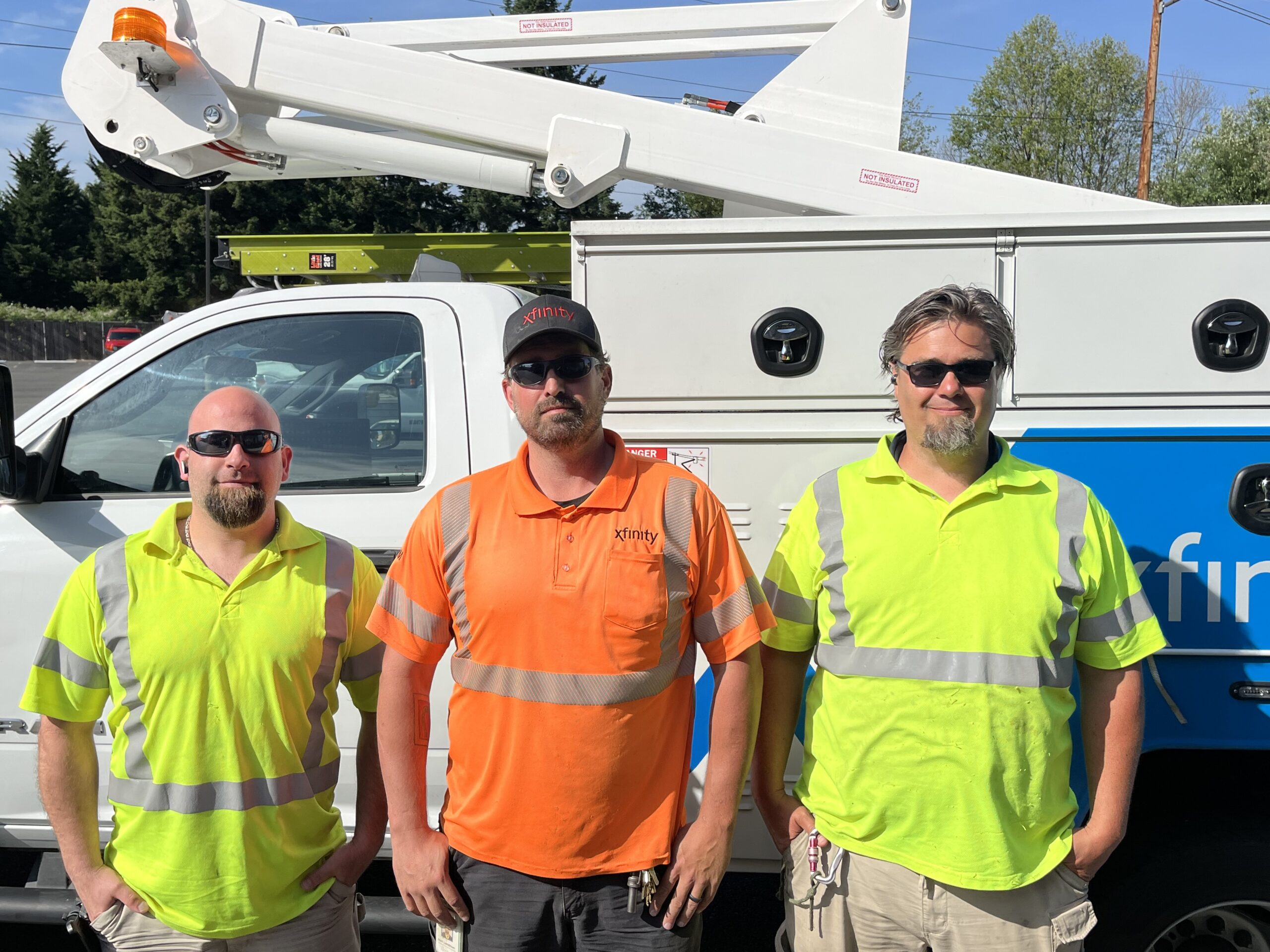 Three Comcast technicians pose in front of an Xfinity truck.