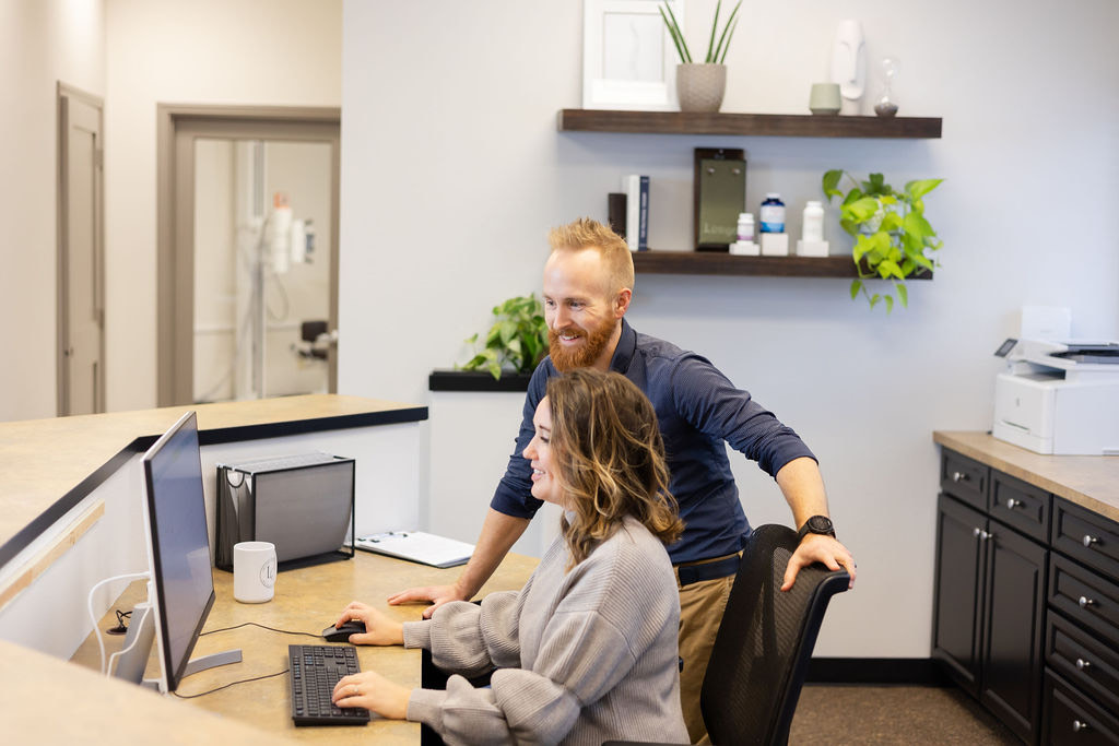 Dr. Mike in the Limitless Chiropractic office at a computer with an employee.