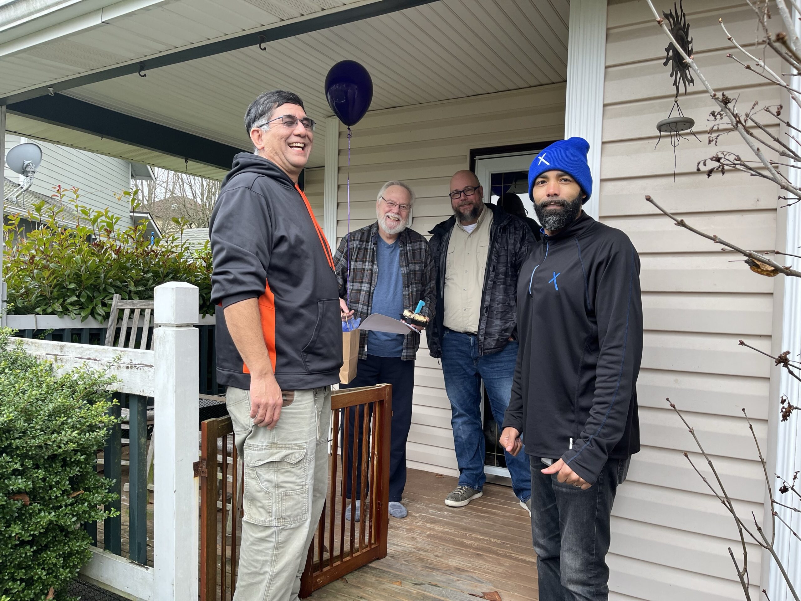 Comcast employees on a porch of a Comcast customer with a balloon..