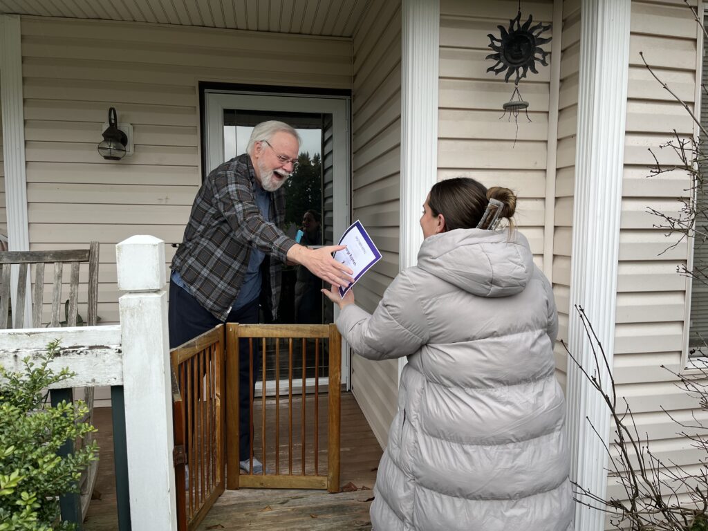 A Comcast customer receives a certificate from a Comcast employee on his porch. 