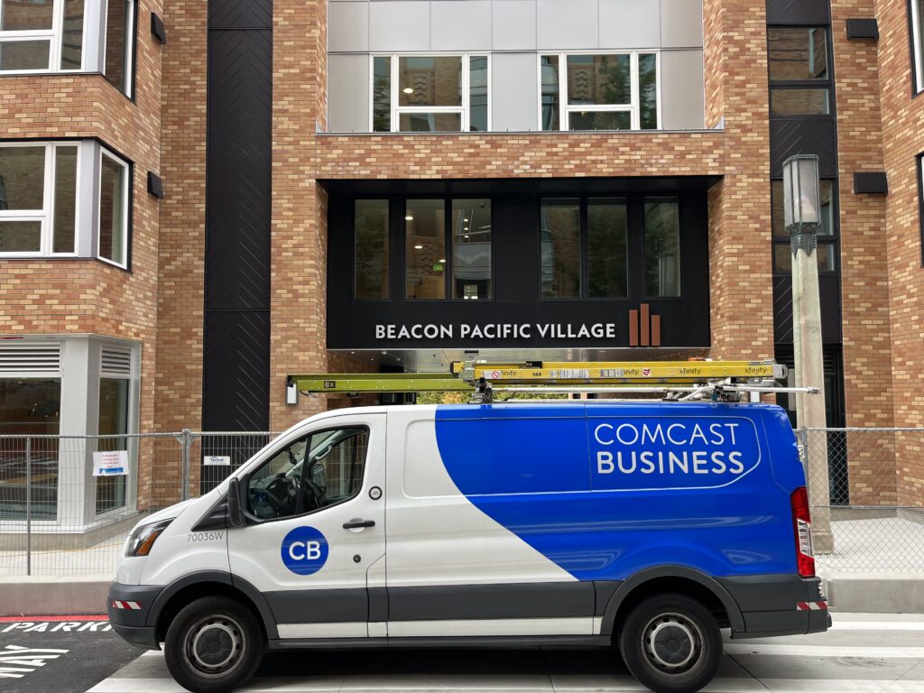 A Comcast Business van parked in front of the Beacon Pacific Village building.