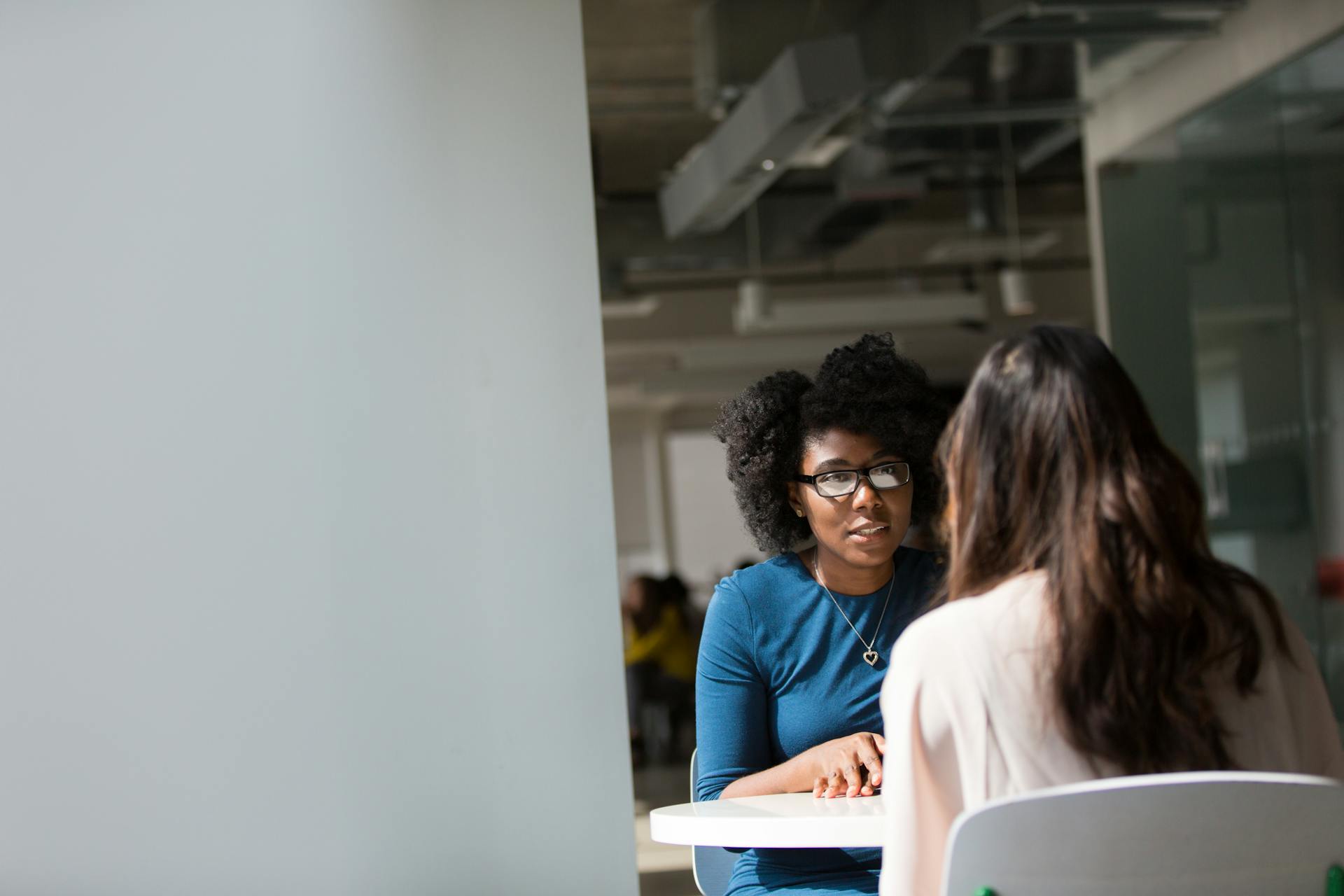 A photo of two women talking in an office.