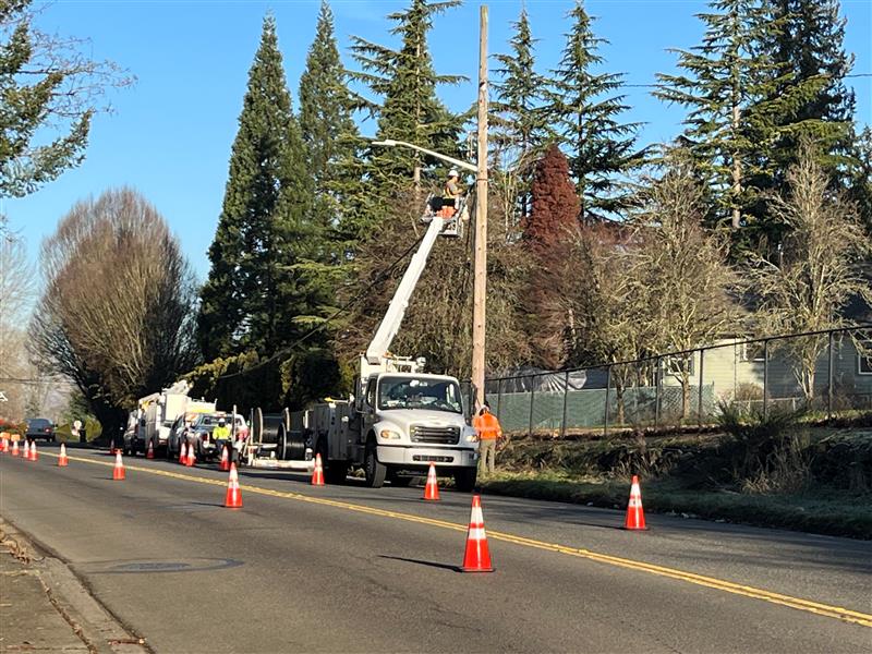 Xfinity bucket truck works on power lines by road.