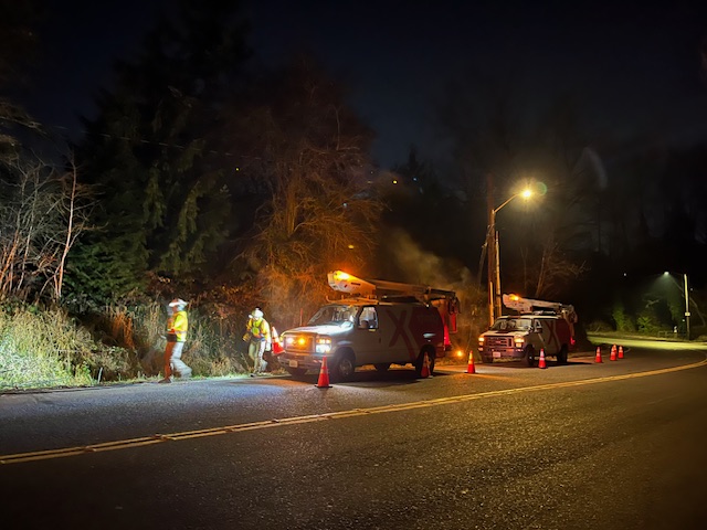 Xfinity team members working on the side of a road in the dark.