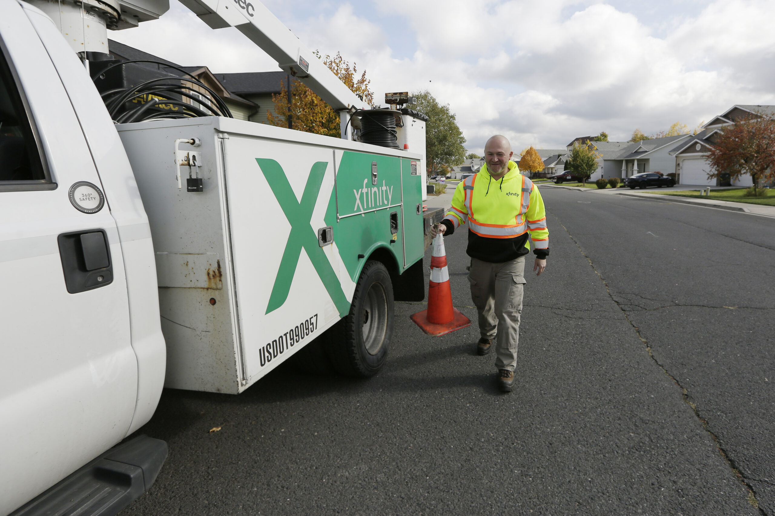 A man carries a parking cone next to an Xfinity truck.