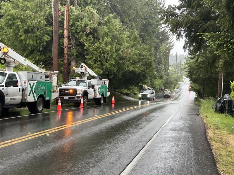Comcast trucks work by the side of the road.