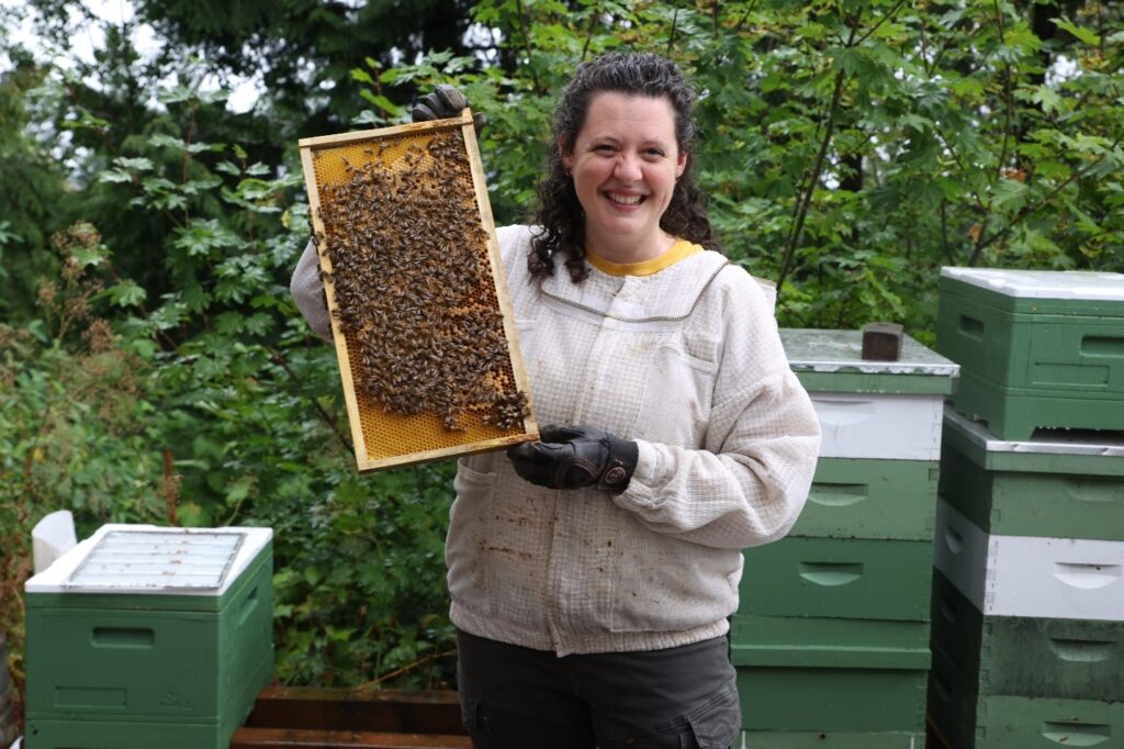 A woman holds up bee honeycomb with honey.
