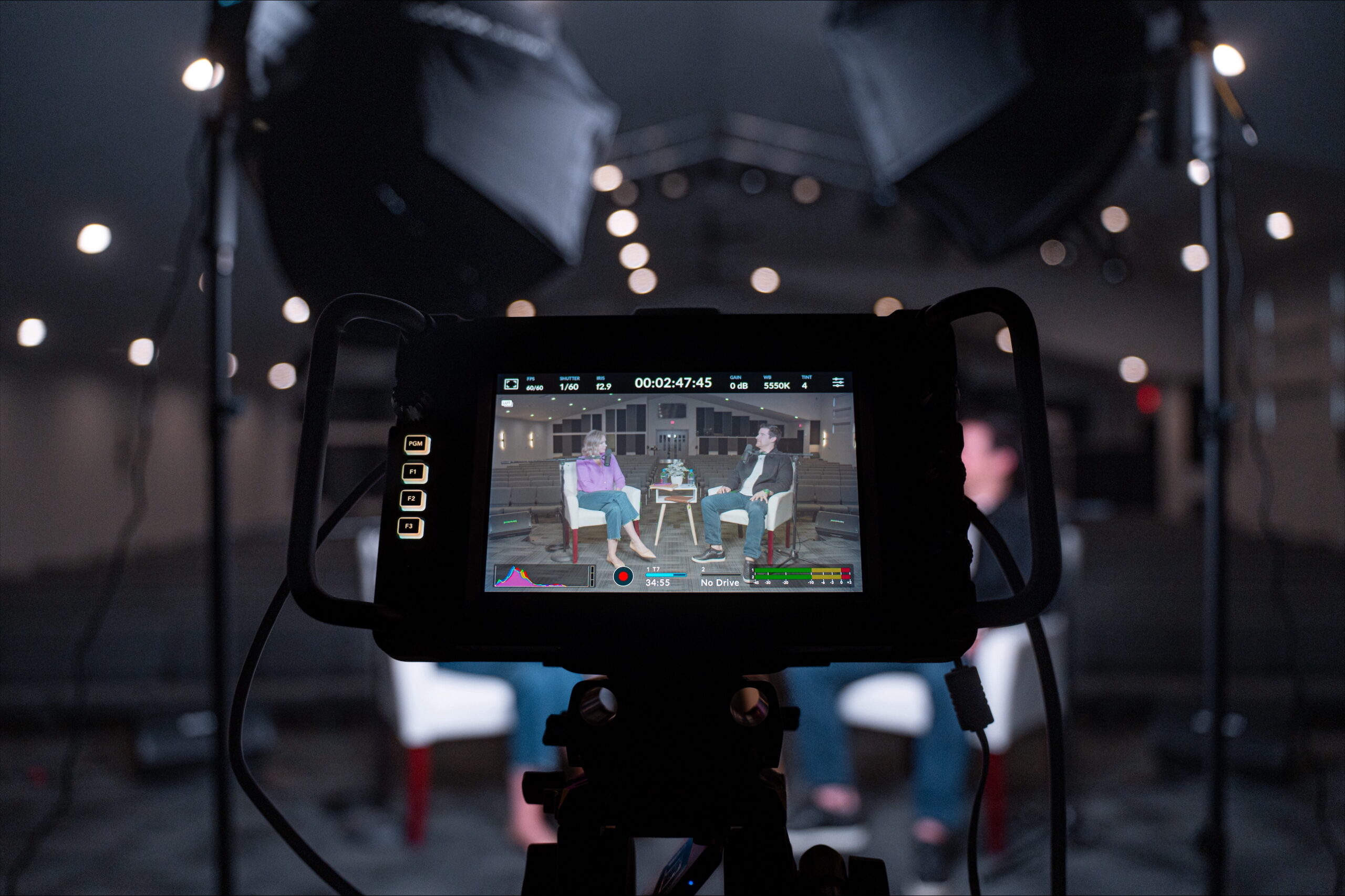 A camera with two people sitting in a church through the lens.